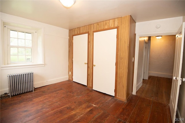 unfurnished bedroom with dark hardwood / wood-style flooring and radiator heating unit