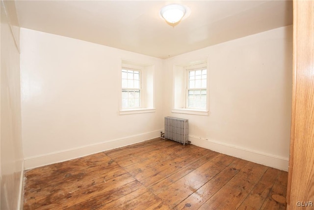 spare room featuring radiator heating unit and hardwood / wood-style floors