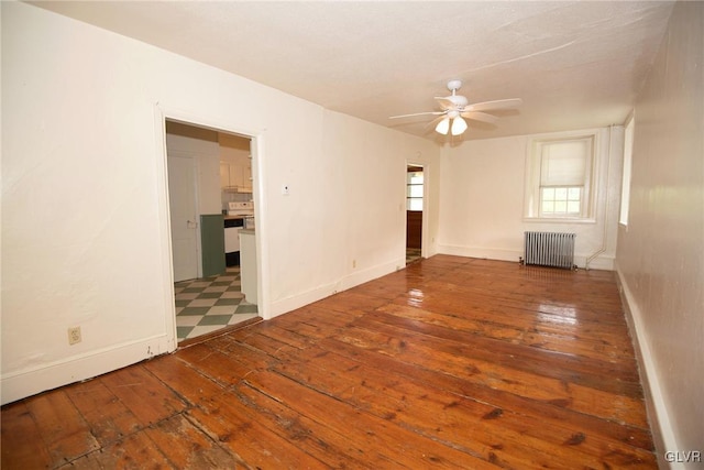 empty room with ceiling fan, radiator heating unit, and hardwood / wood-style flooring