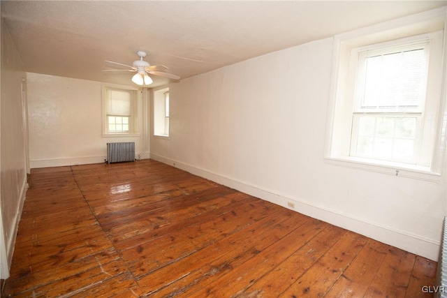 empty room with ceiling fan, radiator heating unit, and dark wood-type flooring