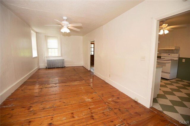 empty room with ceiling fan, radiator heating unit, and hardwood / wood-style flooring