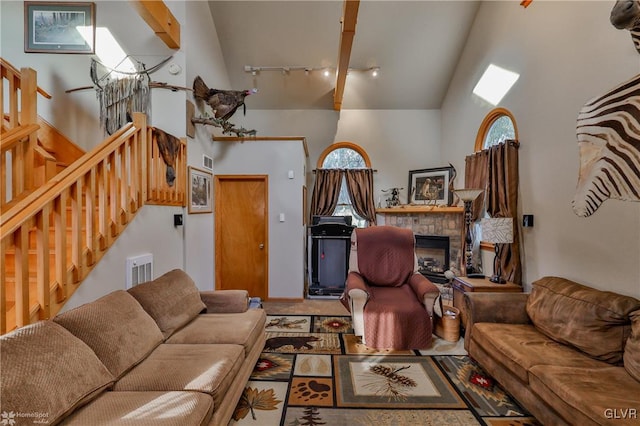 living room featuring beam ceiling, a fireplace, high vaulted ceiling, and track lighting