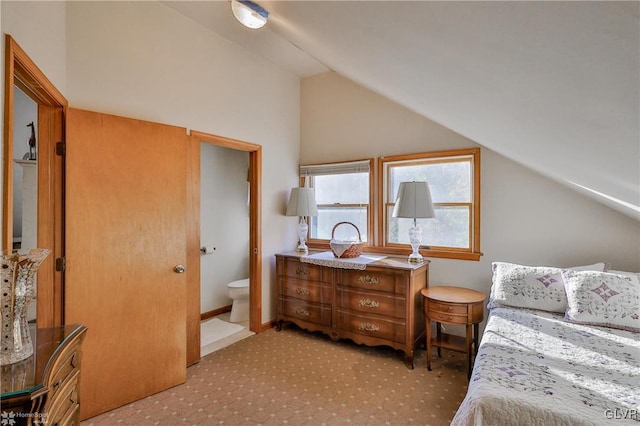 bedroom featuring ensuite bath, light carpet, and lofted ceiling