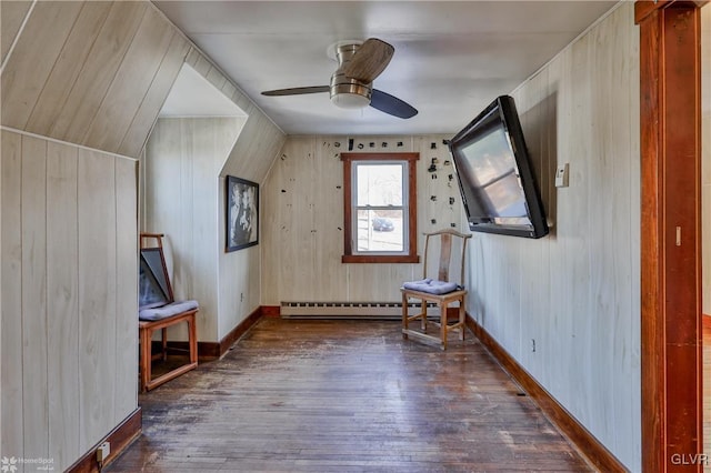 additional living space featuring baseboard heating, wooden walls, vaulted ceiling, and dark hardwood / wood-style floors