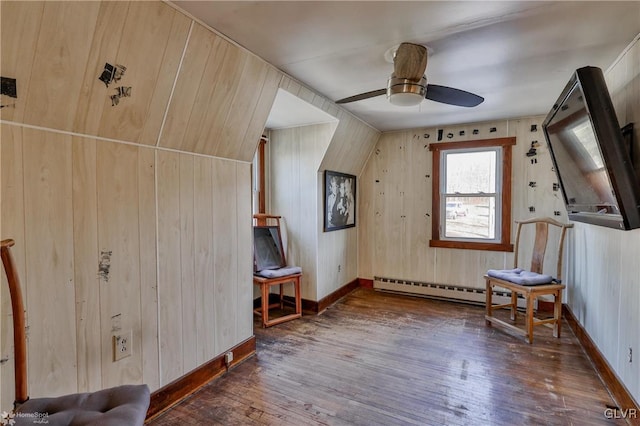 bonus room with a baseboard radiator, dark wood-type flooring, and wood walls