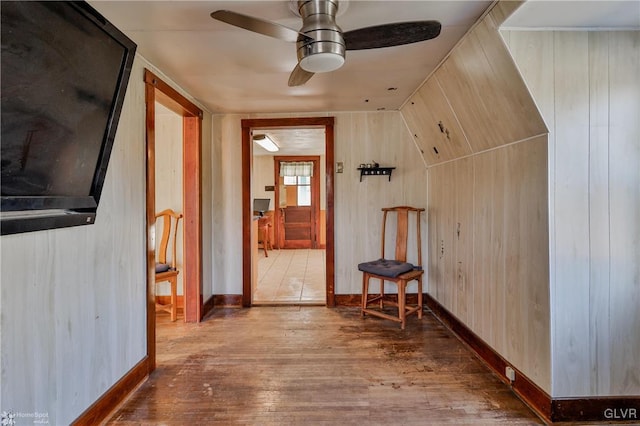 corridor with wooden walls, wood-type flooring, and vaulted ceiling