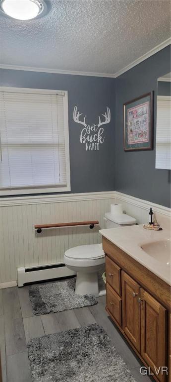 bathroom featuring baseboard heating, crown molding, a textured ceiling, toilet, and vanity