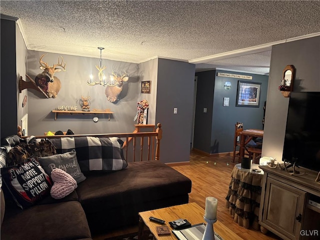 living area featuring a textured ceiling, ornamental molding, wood finished floors, and a notable chandelier