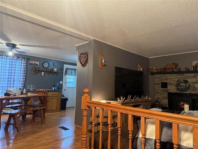 living area with a fireplace, a ceiling fan, wood finished floors, and ornamental molding