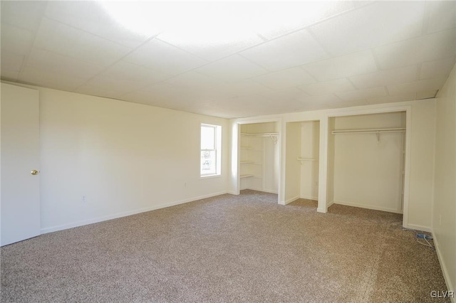 unfurnished bedroom with carpet flooring and two closets