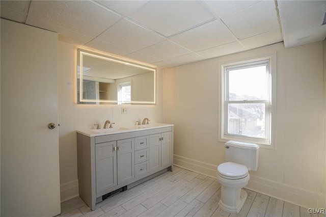 bathroom featuring hardwood / wood-style floors, plenty of natural light, a drop ceiling, and vanity