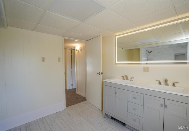 bathroom with hardwood / wood-style floors, vanity, and a drop ceiling