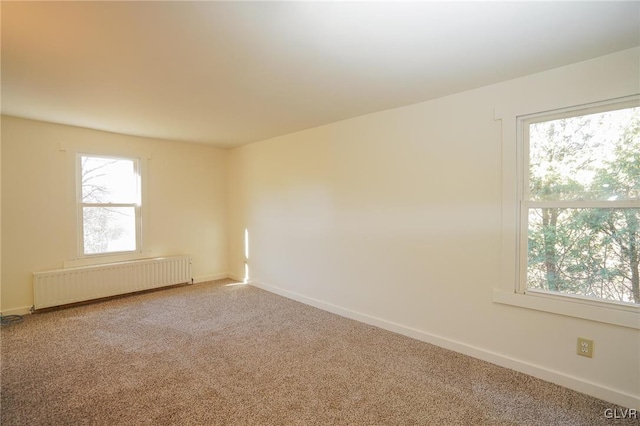 spare room featuring carpet and radiator