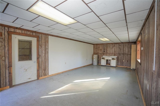 interior space featuring a paneled ceiling, wooden walls, and water heater