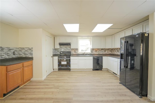 kitchen with black appliances, light hardwood / wood-style floors, white cabinetry, and backsplash