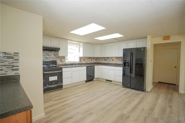 kitchen with backsplash, light hardwood / wood-style flooring, white cabinets, and black appliances