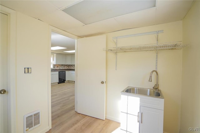 clothes washing area with light wood-type flooring, sink, and wine cooler