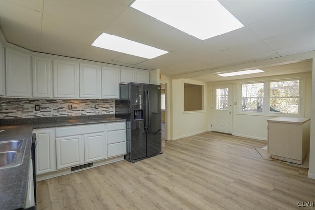 kitchen featuring white cabinetry, black fridge, and light hardwood / wood-style floors