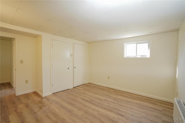 basement with light wood-type flooring and radiator