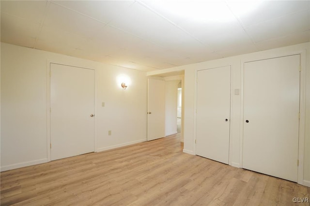 unfurnished bedroom with multiple closets and light wood-type flooring