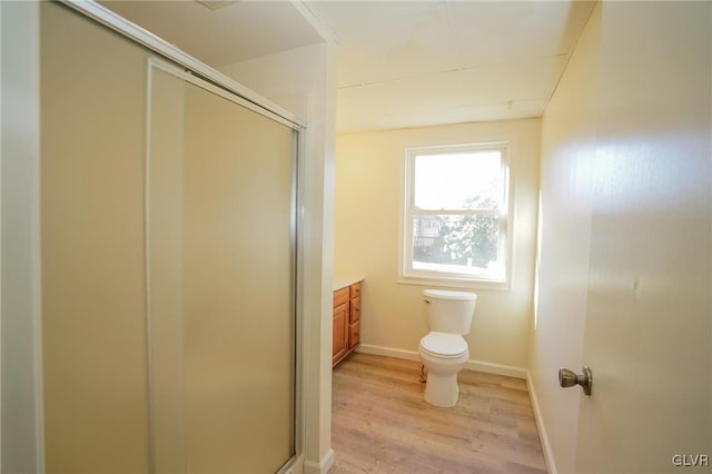 bathroom with a shower with door, vanity, wood-type flooring, and toilet