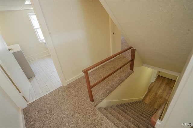 staircase with hardwood / wood-style floors and a textured ceiling