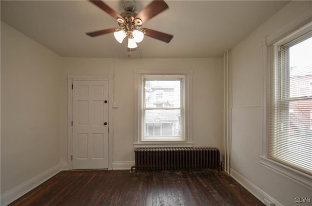 spare room with radiator heating unit, ceiling fan, and dark wood-type flooring