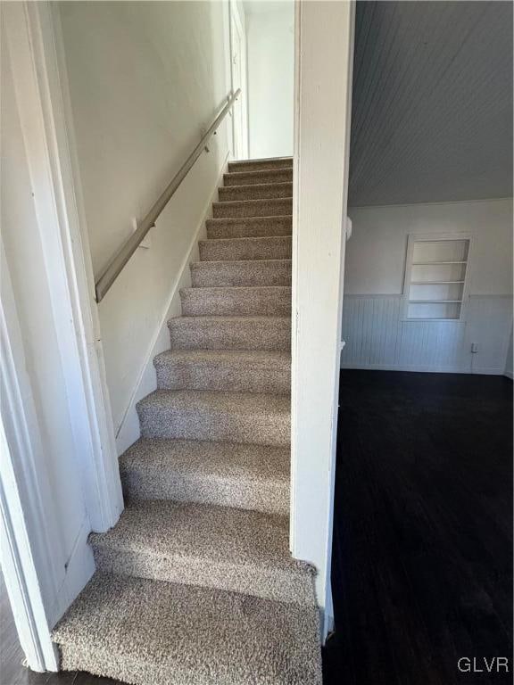 stairs with hardwood / wood-style flooring and wooden walls