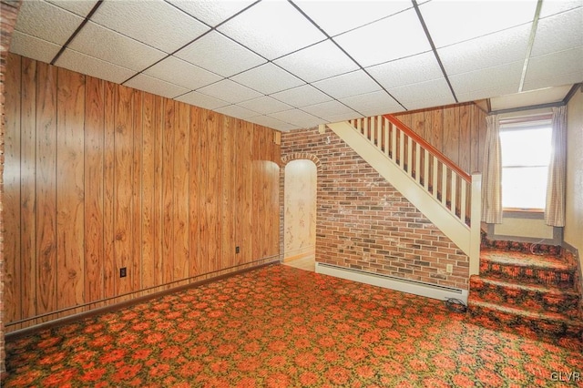 unfurnished living room with wood walls and a drop ceiling