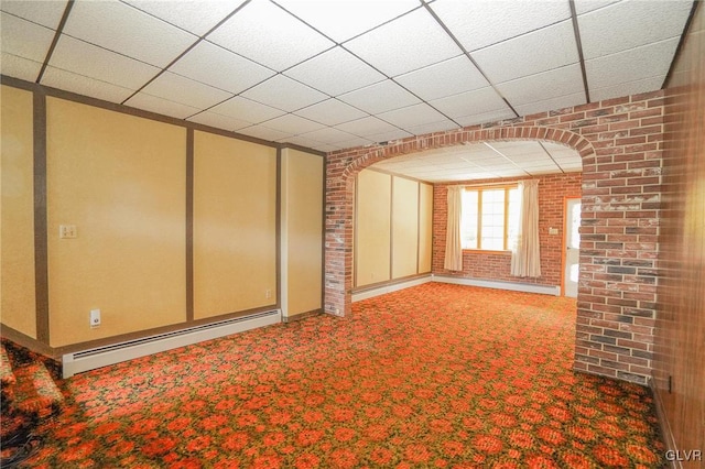 spare room with carpet flooring, a baseboard radiator, a drop ceiling, and brick wall