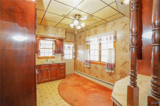 kitchen featuring a paneled ceiling, ceiling fan, sink, and a baseboard radiator