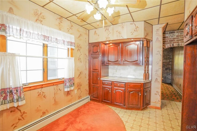 kitchen featuring a drop ceiling, ceiling fan, brick wall, and a baseboard heating unit