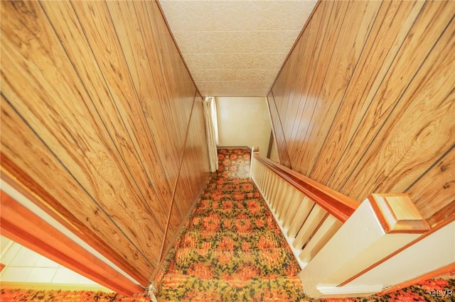 staircase featuring wood walls