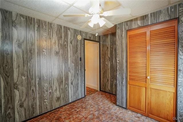 unfurnished bedroom featuring a closet, ceiling fan, and wooden walls