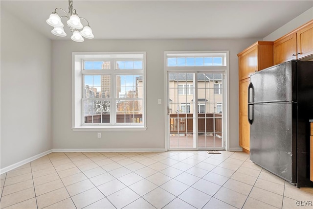 kitchen featuring a chandelier, light tile patterned floors, black fridge, and hanging light fixtures