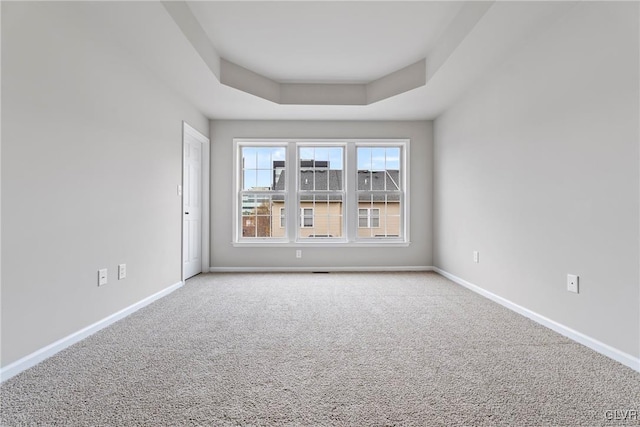 carpeted empty room with a raised ceiling