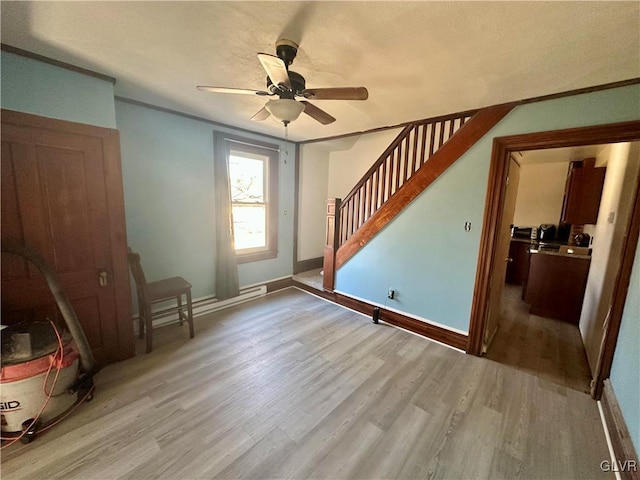 interior space with baseboard heating, ceiling fan, and light wood-type flooring