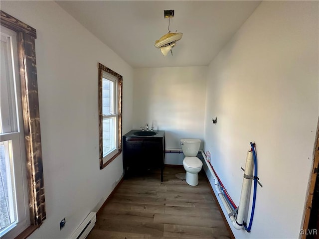 bathroom featuring vanity, hardwood / wood-style floors, baseboard heating, and toilet