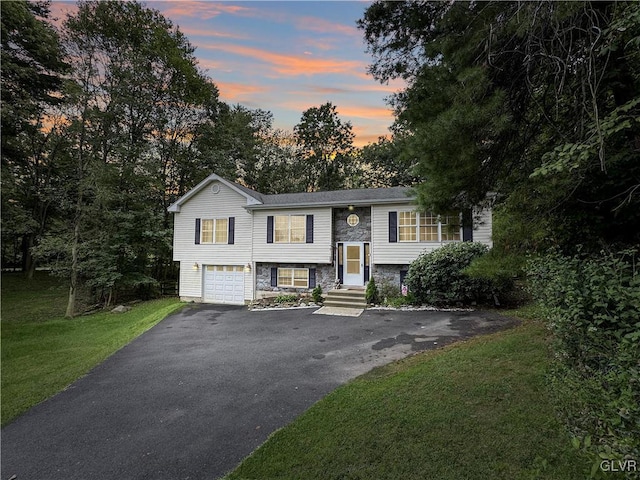 bi-level home featuring a garage and a yard