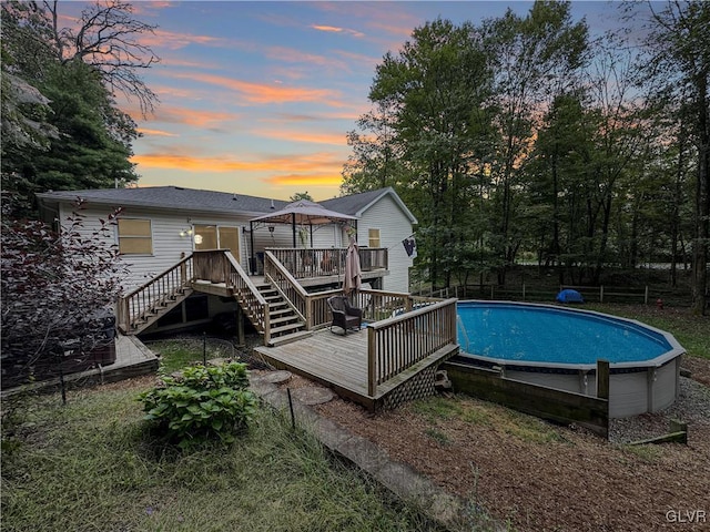 pool at dusk featuring a gazebo and a deck