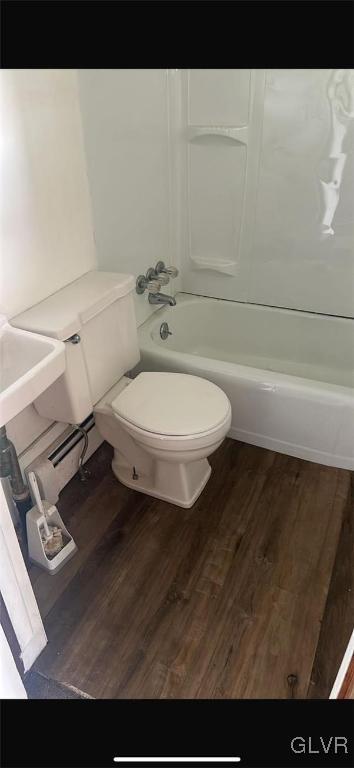 bathroom with hardwood / wood-style floors,  shower combination, and toilet