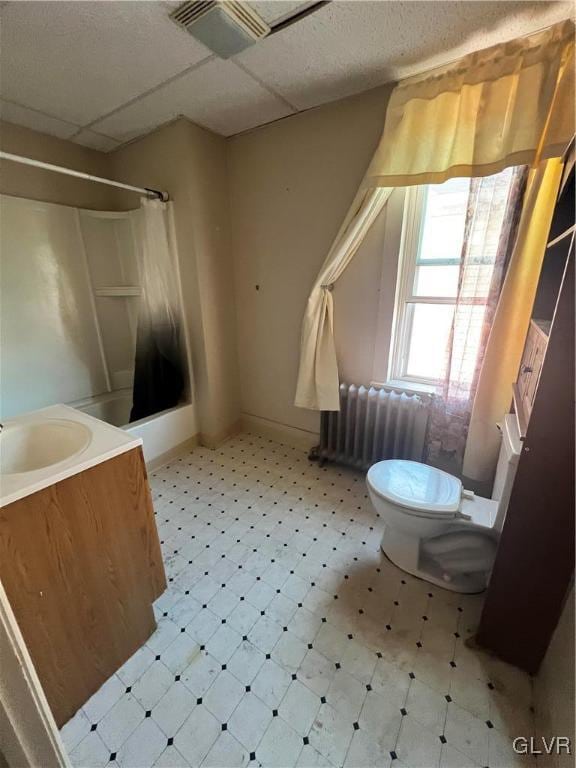 full bathroom featuring vanity, a drop ceiling, shower / bath combination with curtain, toilet, and radiator heating unit