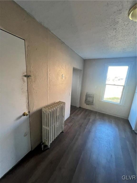 empty room with radiator heating unit, dark hardwood / wood-style floors, and heating unit