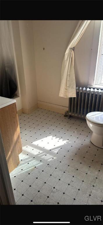 bathroom featuring radiator heating unit and toilet