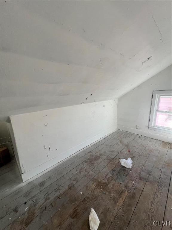 additional living space with hardwood / wood-style flooring and lofted ceiling