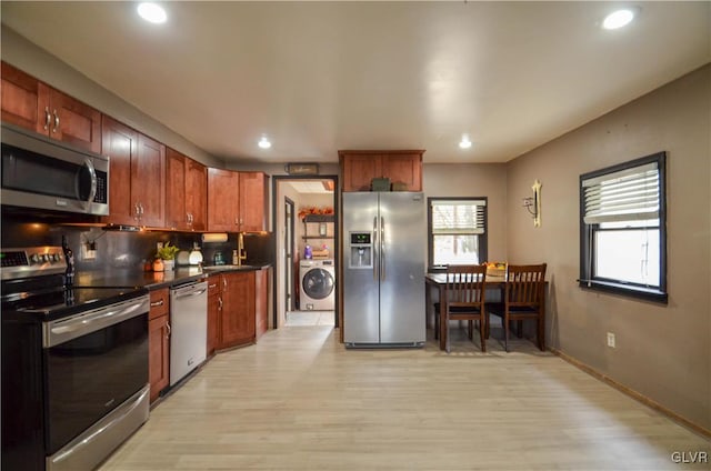 kitchen featuring plenty of natural light, light wood-type flooring, stainless steel appliances, and washer / clothes dryer