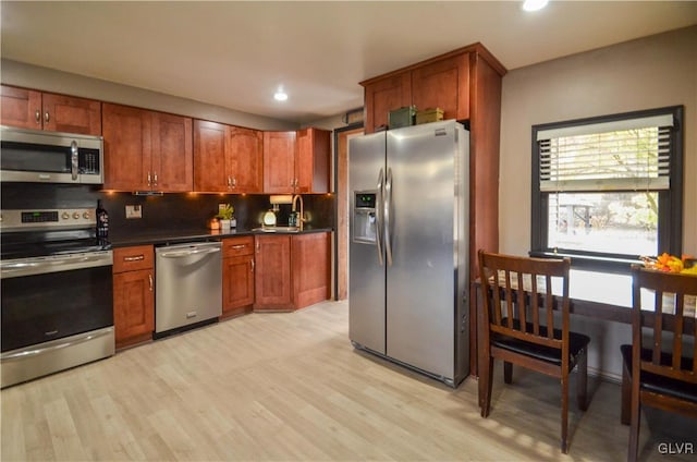 kitchen with light hardwood / wood-style floors, sink, appliances with stainless steel finishes, and tasteful backsplash