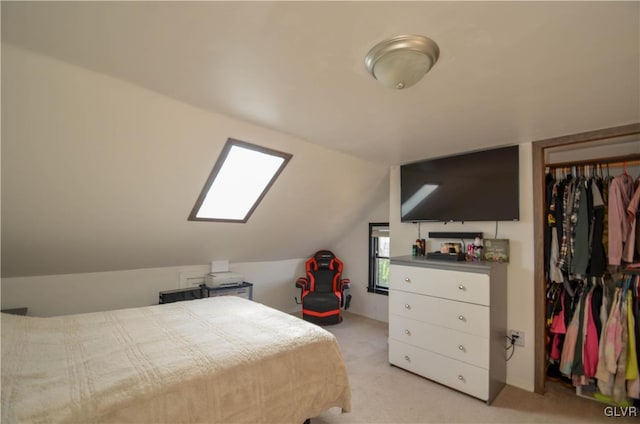 bedroom with a closet, light carpet, and vaulted ceiling with skylight