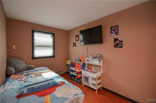 bedroom featuring hardwood / wood-style flooring and a baseboard heating unit