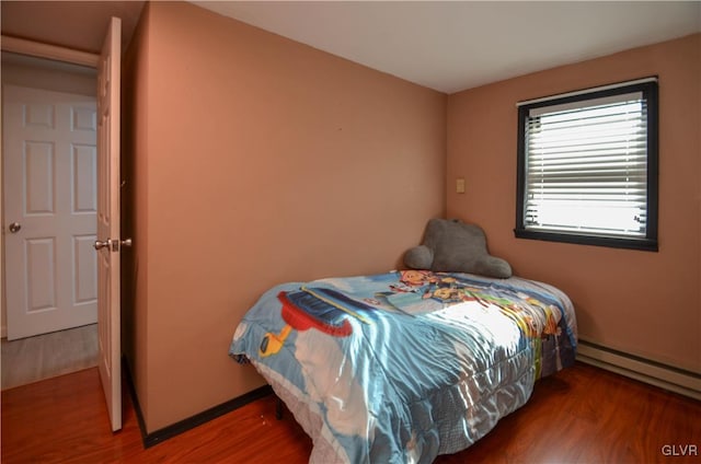 bedroom with dark hardwood / wood-style flooring and baseboard heating